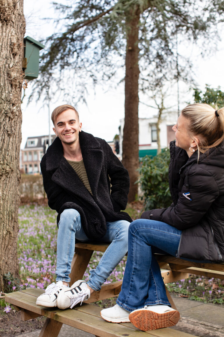Michel zittend en lachend op een picknicktafel